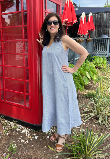 Tara in a navy blue and white pinstripe maxi dress. The dress is sleeveless with a collar and v-neckline.  