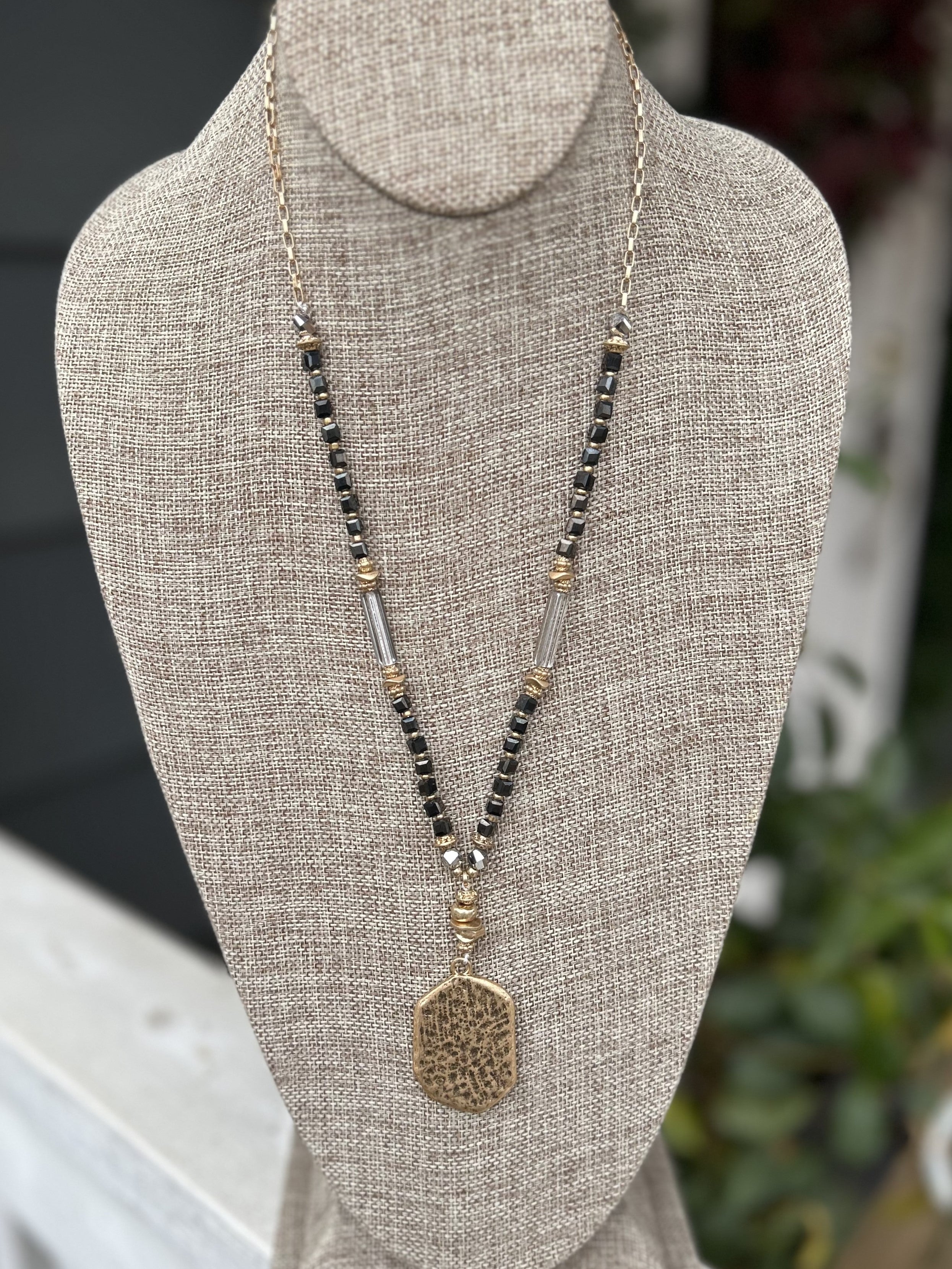 Take your look to the next level with this elegant Black & Gold Long Necklace. Crafted with a unique chain composed of differing shapes, it's finished off with a statement hammered gold drop that offers a perfect bit of sparkle. A classic combination of black, gold and clear, this necklace will turn heads.   Approximate Length: 30-32"