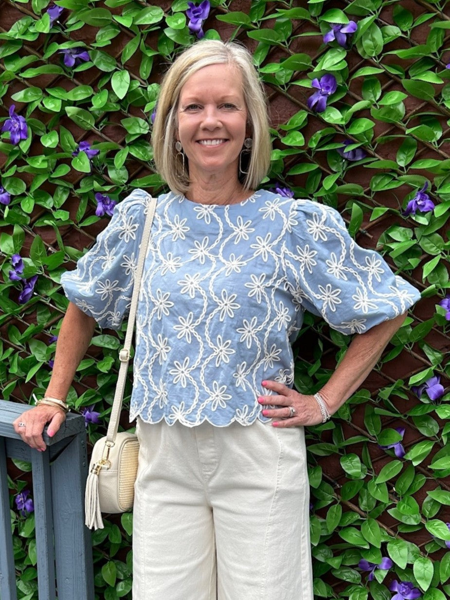 You will love this charming blue and white embroidered top. Delicate embroidery adorns the fabric, while elbow-length sleeves offer a refined silhouette. The scalloped hem adds a feminine touch that pairs beautifully with white jeans, white shorts, or linen pants. A versatile piece that transitions effortlessly from day to evening, this top brings understated elegance to any outfit.

Barbara is wearing a size Small.

Material: 100% Cotton

Care Instructions: Gentle cool hand wash cold, dry flat