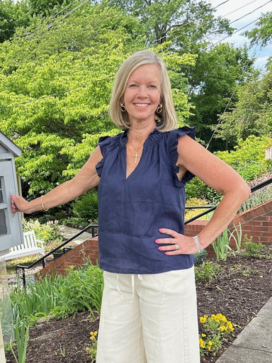 You will love the playful style in this navy linen top. Crafted from breathable linen fabric, it features a flattering V-neckline and charming ruffled cap sleeves that add movement and dimension. The rich navy hue works beautifully for patriotic occasions, game day gatherings, or everyday wear. Perfect for warm weather, this versatile piece transitions seamlessly from casual outings to festive celebrations.

Material: 100% Linen

Care Instructions: Hand wash, hang to dry