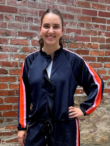 How adorable is this "track suit!" with all of it's fun style! The silky feel of the fabric is so soft and flowy. The shorts with their orange and pink side stripes have an elastic waist with a drawstring are super cute and flattering! The jacket has a full zipper with a ruffle accent and those same bold stripes from the shoulder to the wrist. It's a fabulous set!

Grier is wearing a small in each piece.&nbsp;

Sold as a set.

Material: 100% Polyester

Care Instructions: Gentle cool hand wash, dry flat