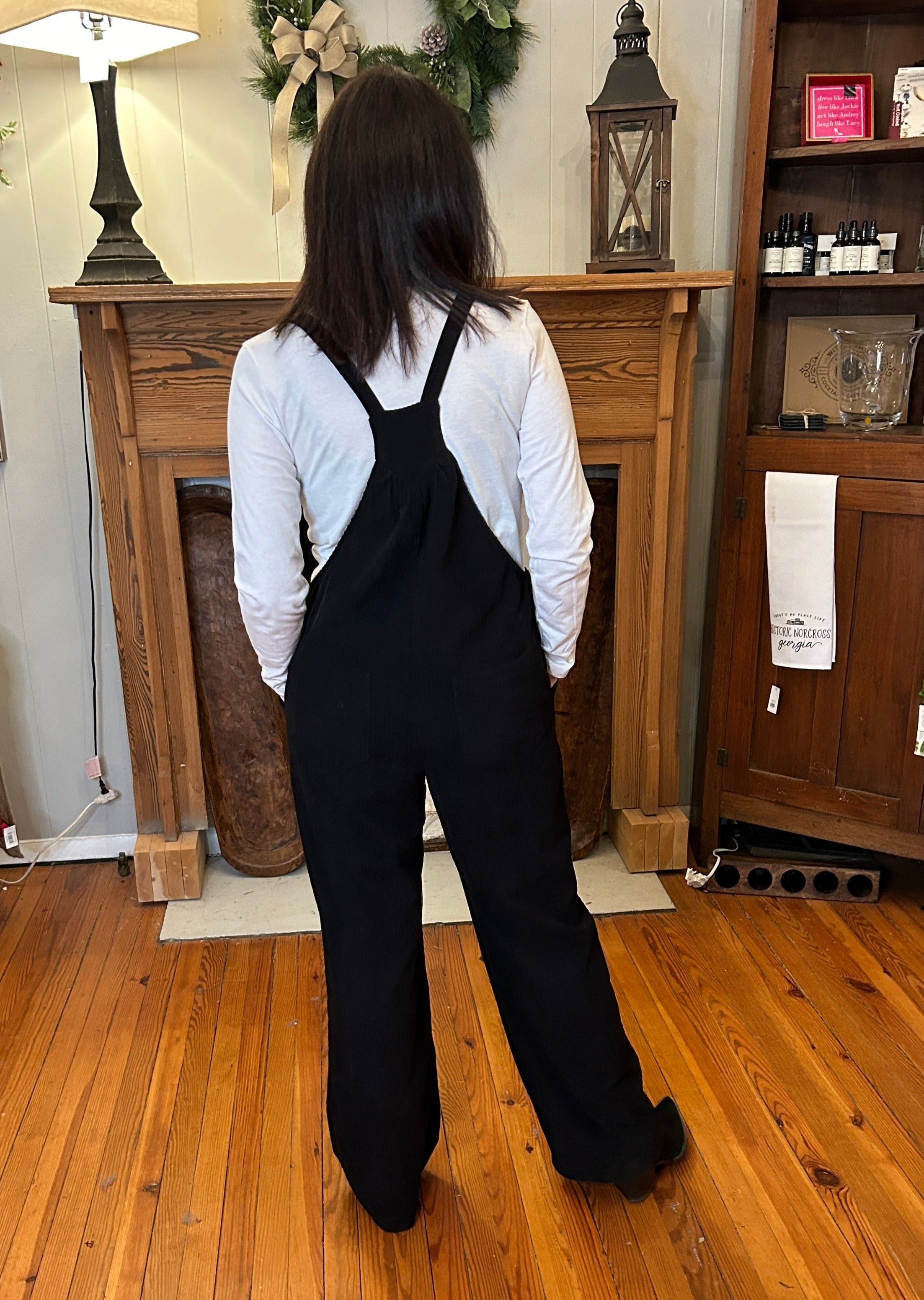 Back view of black cord overalls.