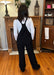 Back view of black cord overalls.
