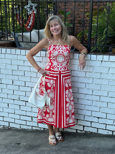Carolee is wearing a red & Ivory print sundress with a cute white bag and sandals. The midi dress has an awesome print. rushing in the back and spaghetti strapts.  She is wearing a small.