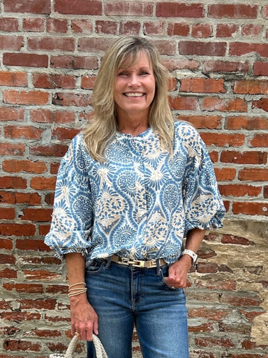 Discover timeless style with this damask print button-down blouse in serene blue tones. The classic damask pattern brings an air of sophistication to your everyday look, while the graceful balloon sleeves add a touch of romance and movement. Crafted for comfort and versatility, this blouse pairs beautifully with denim, tailored trousers, or flowing skirts. Whether you're dressing up for brunch or keeping it casual, this elegant piece is your go-to for effortless, polished style.

Carolee is wearing a size S