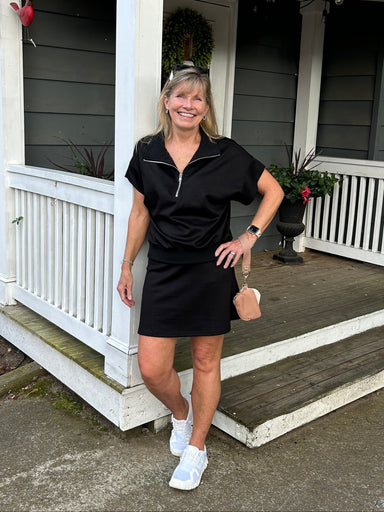 Experience the perfect blend of comfort and functionality with this scuba knit skort. Made from luxuriously soft fabric, it delivers the coverage and ease you need for everything from casual outings to active pursuits. We love the flattering length, the comfortable fit, and the built in short. It pairs perfectly with our quarter zip top for an effortless coordinated look. Your new go-to in classic black.

Carolee is wearing a Small.&nbsp; She paired it with our matching "Scuba Knit Quarter Zip Top".

Materi