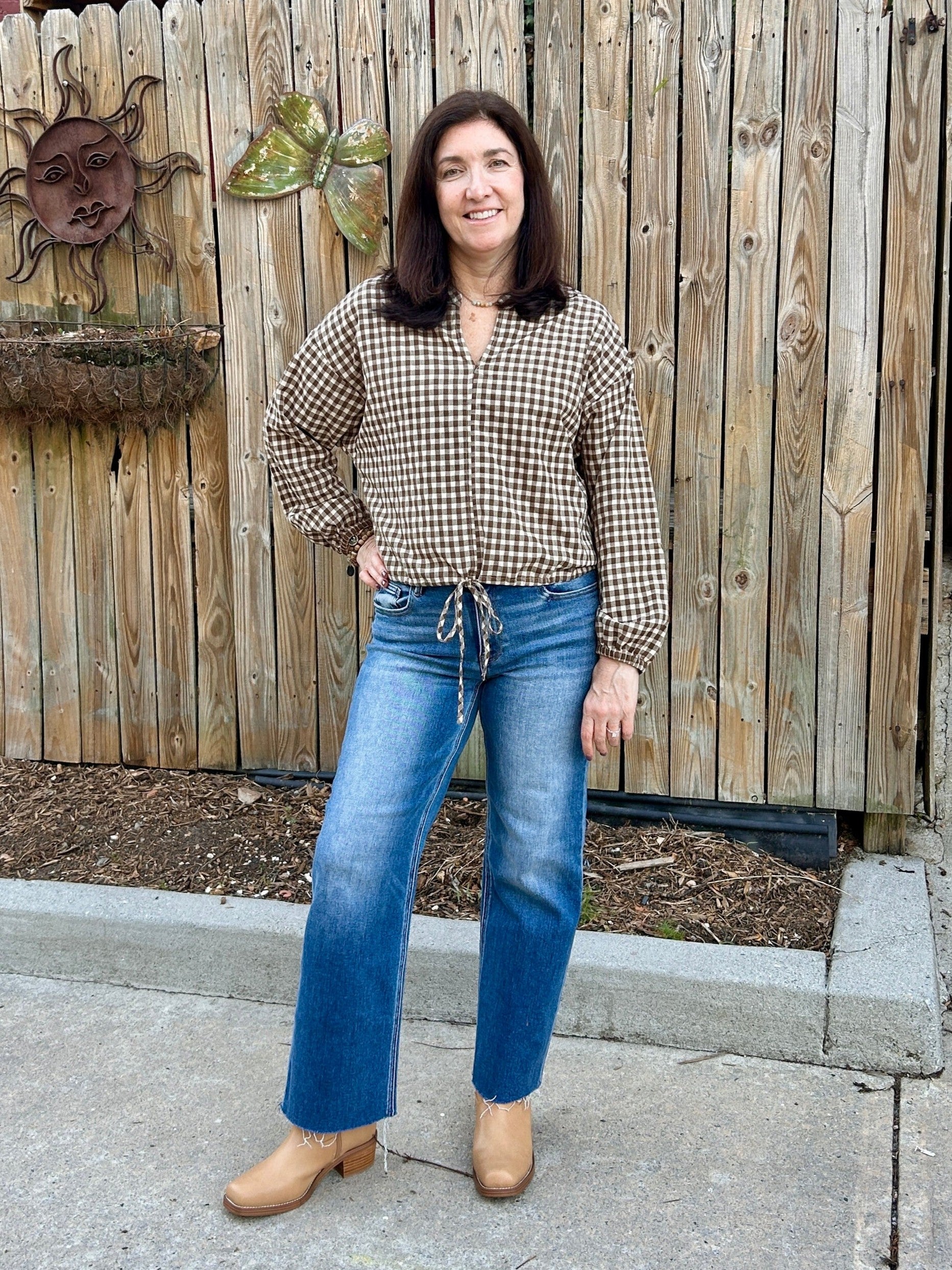 This brown and cream gingham top is so cute and so on-trend! It has great style and fit, is a nice weight and is so versatile. We love the draw string waist, the synched sleeve and the flattering V-neck. It's perfect for fall!

Tara is wearing a small.

Material: 50% Cotton / 50% Polyester&nbsp;

Care Instructions: Hand wash with cold water, line dry