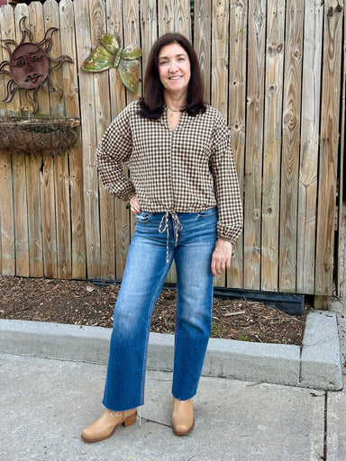 This brown and cream gingham top is so cute and so on-trend! It has great style and fit, is a nice weight and is so versatile. We love the draw string waist, the synched sleeve and the flattering V-neck. It's perfect for fall!

Tara is wearing a small.

Material: 50% Cotton / 50% Polyester&nbsp;

Care Instructions: Hand wash with cold water, line dry