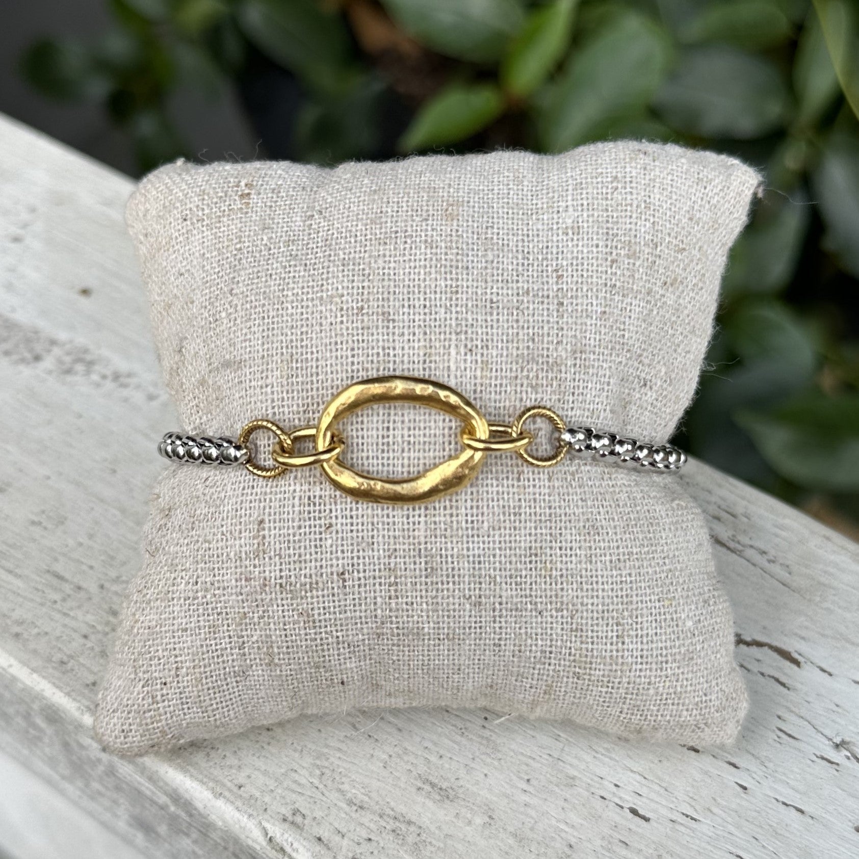 This mixed metal bracelet features an eye-catching gold hammered oval accent on a smaller silver chain, creating a unique look. It is adjustable and versatile, allowing you to wear it with both silver and gold jewelry. You will love this stunning piece!

Designed and made by local artist