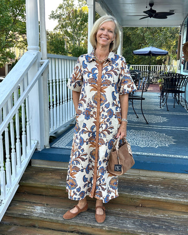 Timeless florals meet everyday comfort in this cream button-up midi dress. The charming blue and brown floral print pairs beautifully with a polished collared neckline and placket front detail. Lightweight, fully lined fabric ensures all-day comfort and confidence, while short sleeves and a relaxed straight cut make it effortlessly versatile. Whether you're running errands or enjoying warm-weather gatherings, this dress transitions seamlessly from casual to put-together.

Material: 100% Cotton

Care Instruc