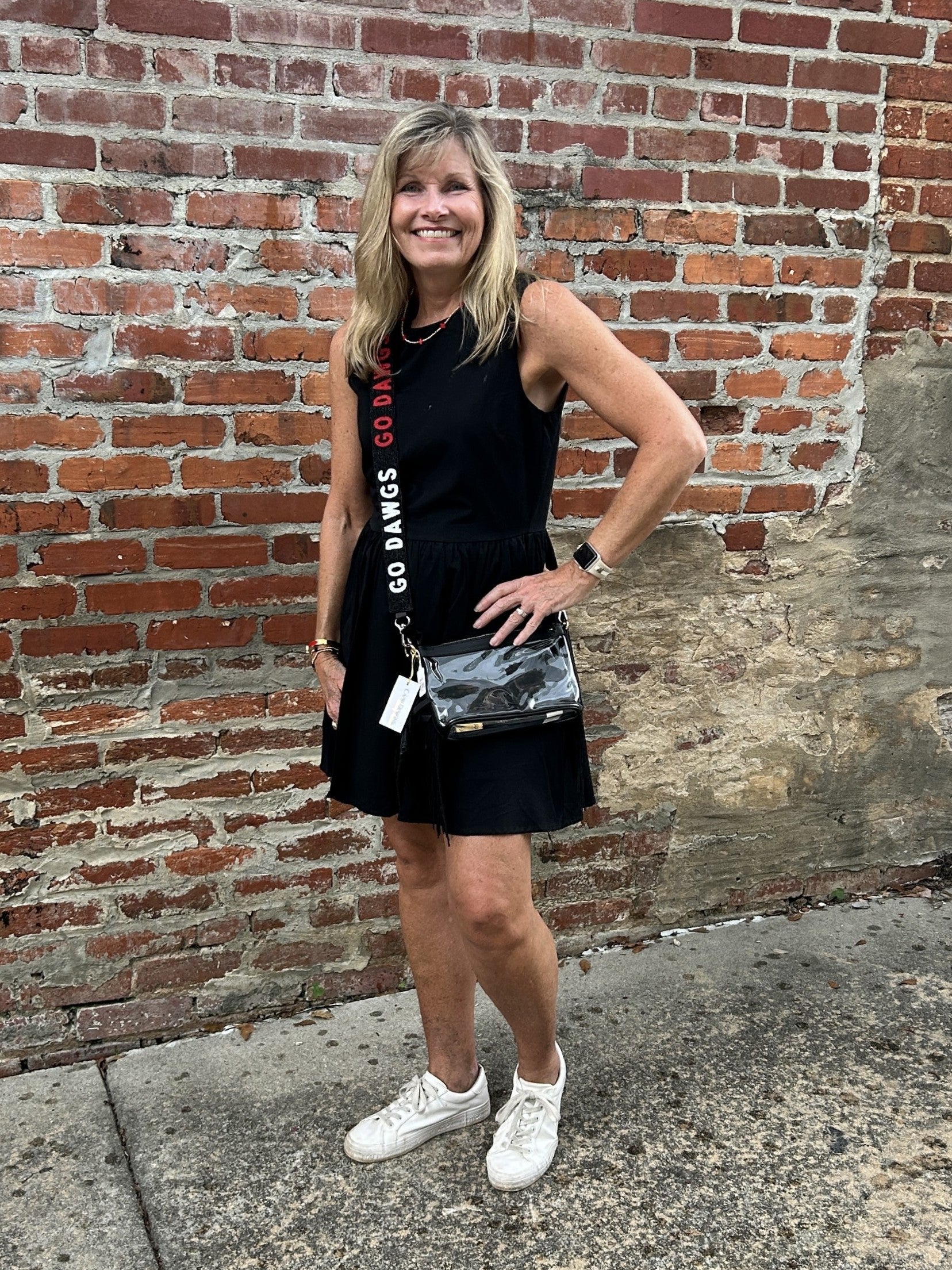 This black sleeveless mini dress offers a flattering silhouette that effortlessly enhances your figure. Perfectly lined for comfort, it features convenient side pockets to keep essentials close. Whether you're gearing up for game day or planning a stylish evening out, this dress combines practicality with chic appeal to keep you looking and feeling confident.

Carolee is wearing a size Small. She has accessorized with our Gold Beaded Necklace w/ Small Crosses (red), Bag/Purse Straps: Game Day Beaded (GO DAW