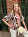 This Short Sleeve Ornate Design Top showcases a beautiful brown and beige print, perfectly capturing the warmth of fall colors. Its contrasting velour V-neckline adds a rich texture, while the short puffy sleeves with elastic closures create a flattering silhouette. Ideal as a stylish transition piece, this top effortlessly blends comfort and elegance for your seasonal wardrobe.

Barbara is wearing a size XSmall. She paired the top with our "Erin Wide Leg Denim/Pants in Oat. She added our "Marla Leather Raf