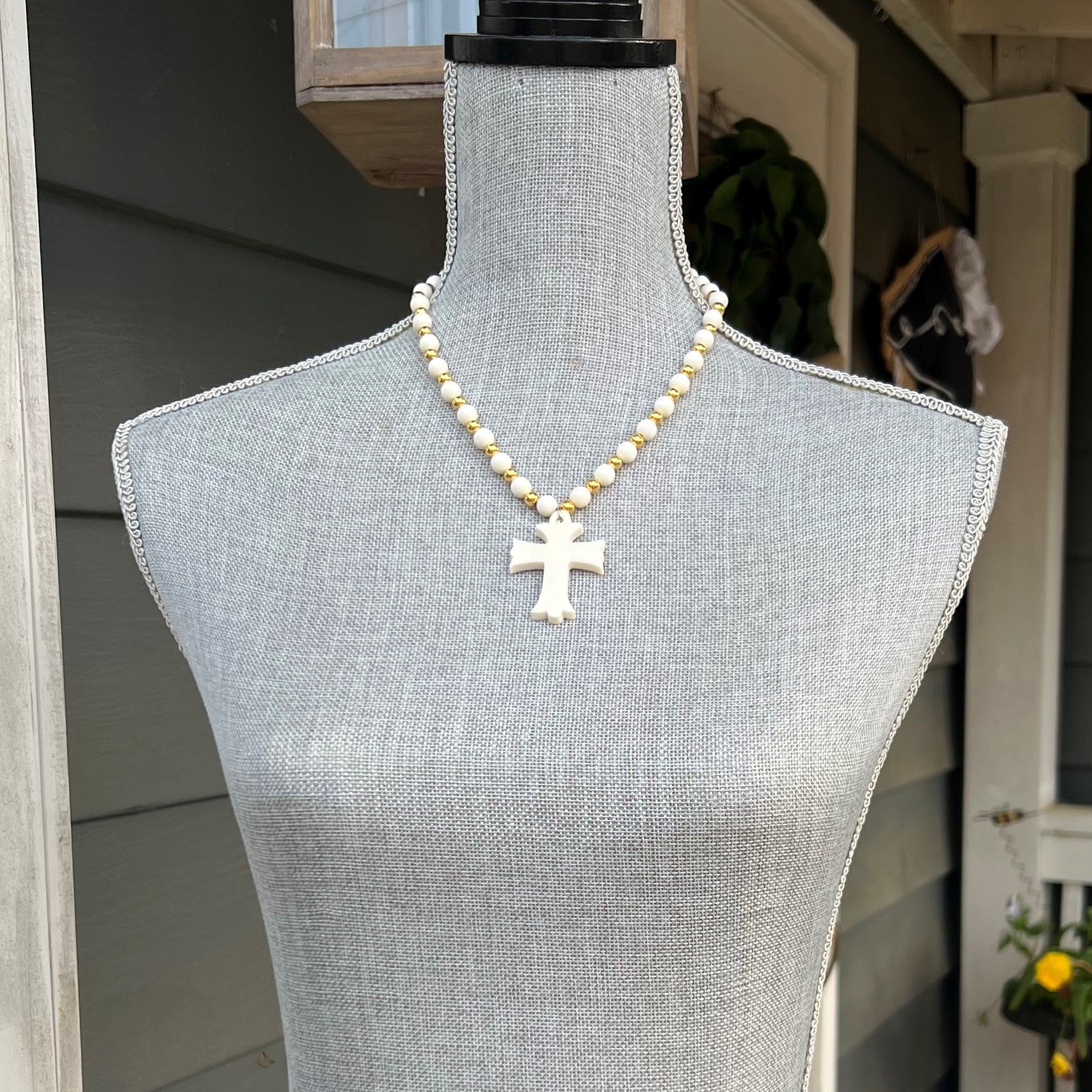 This luxurious necklace is handcrafted with camel bone and gold beads and detailed with an intricately hand-carved cross. The sophisticated materials make this necklace an exquisite addition to any wardrobe.  Approximate Lengths:  Long: 32" Short: 20"