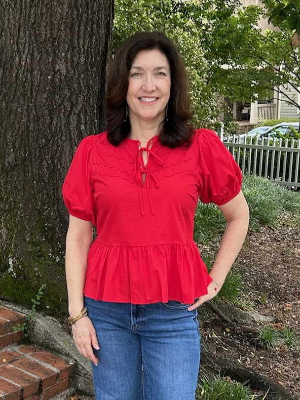 Get game day ready with the Ric Rac Front Tie Top, perfect for celebrating the 4th of July in style. Featuring playful ric rac detailing, a tiered bodice, and charming puffed sleeves, this top combines festive flair with comfortable wear. The front ties add a flattering touch, making it an ideal choice for fun summer gatherings and patriotic events.

Tara is wearing a size small.

Material: 100% Polyester

Care Instructions: Hand wash cold, hang to dry