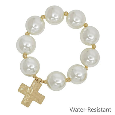 Large pearl beads create a striking statement, complemented by a delicate hammered cross charm. The stretch design slips on effortlessly for everyday wear or special occasions.