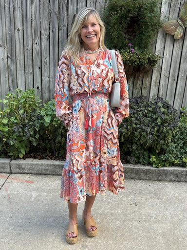 This gorgeous Printed Tassel Tie Neck Midi Dress is a must-have! The beautiful peach and multi-colored design is eye-catching. The midi length and tiered skirt add a touch of elegance, while the lightweight and lined fabric make it perfect for the fall season. The unique gathered cuffs and neckline add a charming touch to this dress, making it the perfect addition to your wardrobe.

Material: 70% Tencel / 30% Nylon; Lining 100% Cotton

Care Instructions: Hand wash separately in cold water, hang to dry