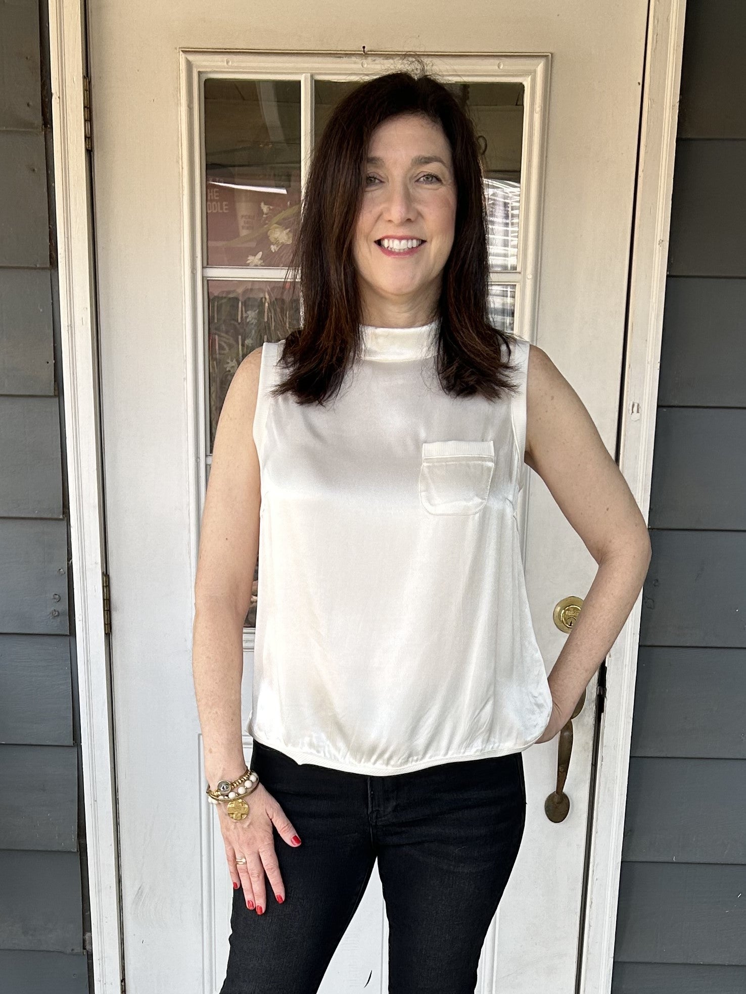 Discover effortless elegance with our Sleeveless Satin Top in a stunning cream color. The silky and soft material brings both comfort and luxury, making it a staple in your wardrobe. Perfectly accented with ribbed trim and a back button closure, this top is sure to make you feel pretty.  Material: 100% Viscose; Trim: 95% Cotton/ 5% Spandex&nbsp;  Care Instructions: Hand wash cold, hand to dry
