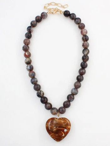 Discover the perfect blend of natural beauty and heartfelt style with this exquisite dark brown beaded necklace. Handcrafted with warm, earthy beads and anchored by a breathtaking natural stone heart pendant, this piece radiates understated elegance. The rich brown tones create a versatile foundation that pairs effortlessly with any outfit, while the meaningful heart centerpiece adds a personal touch of sophistication.

Chain length: 16-18"