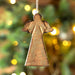Bring traditional meaning into your home with this beautifully carved wooden angel ornament. With it's bronze sheen and careful craftsmanship, this ornament will remind you of the holiday season year round. Give your home the gift of tradition this year!  Approximate size: 3.5" x 6" x .5"