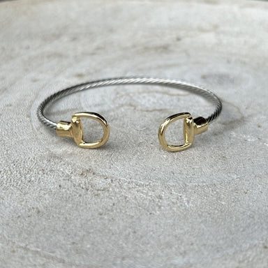 Effortless elegance meets versatile style with this mixed metal cuffed bracelet. Crafted in warm gold and cool silver tones, the design features a distinctive stirrup accent that adds visual interest to any wrist. The flexible, bendable construction ensures a comfortable fit for most sizes, while the cuff style makes it simple to slip on and off. Layer it with other pieces or wear it solo for an understated, sophisticated look.

Note: Silver N' Accessories jewelry is brass and stainless steel with rhodium a
