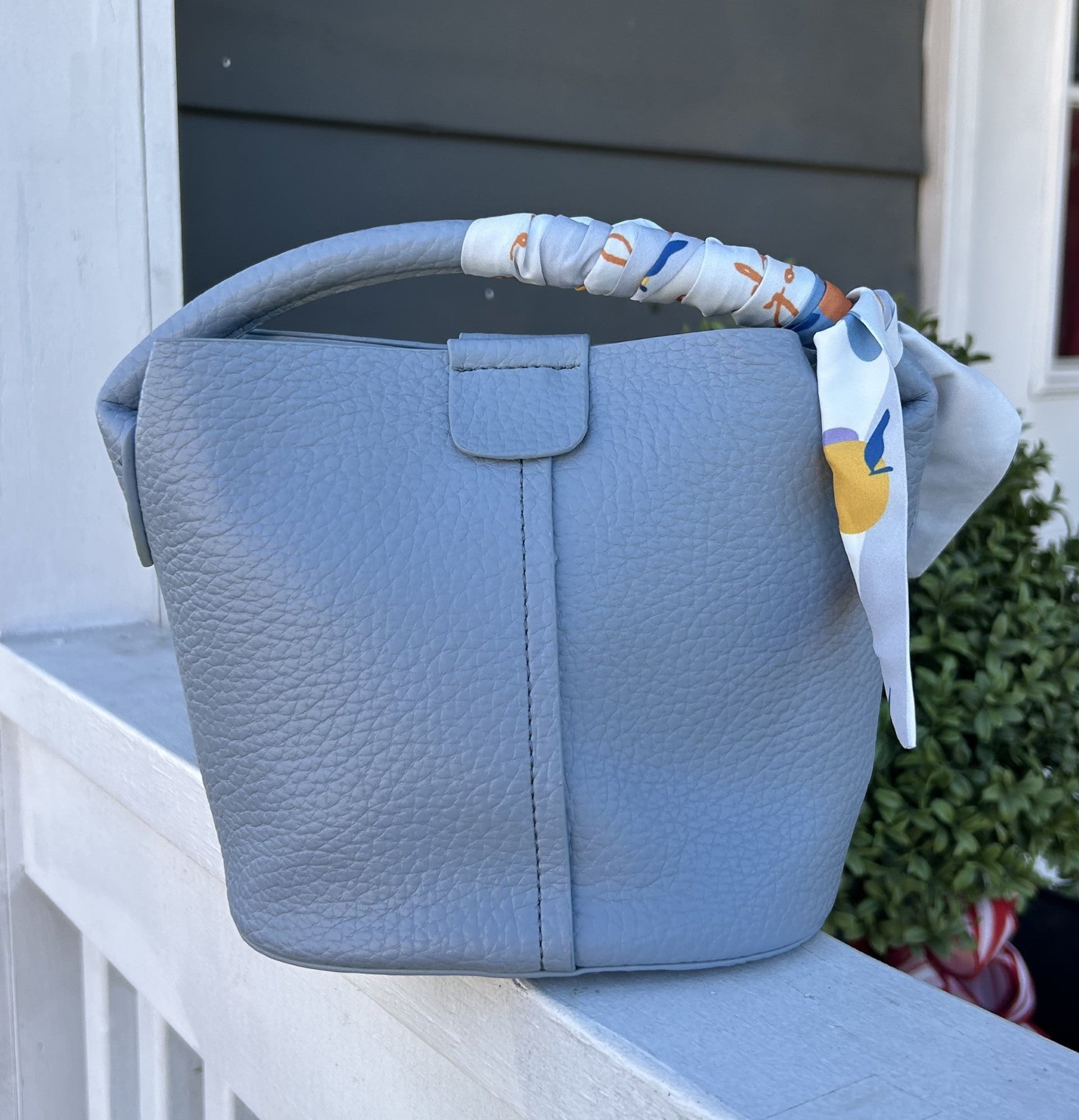 Blue textured handbag with a colorful strap on a white surface