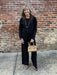 A sophisticated black button-up sweater and matching pants set designed for versatility. The sweater doubles as both a polished cardigan and standalone piece, featuring a detachable faux fur collar that adds instant glamour for special occasions or removes for everyday wear. Crafted from lightweight sweater material, the entire set is ideal for layering or wearing solo. The coordinated pants share the same premium fabric, creating a cohesive, elevated look that transitions seamlessly from casual days to ele
