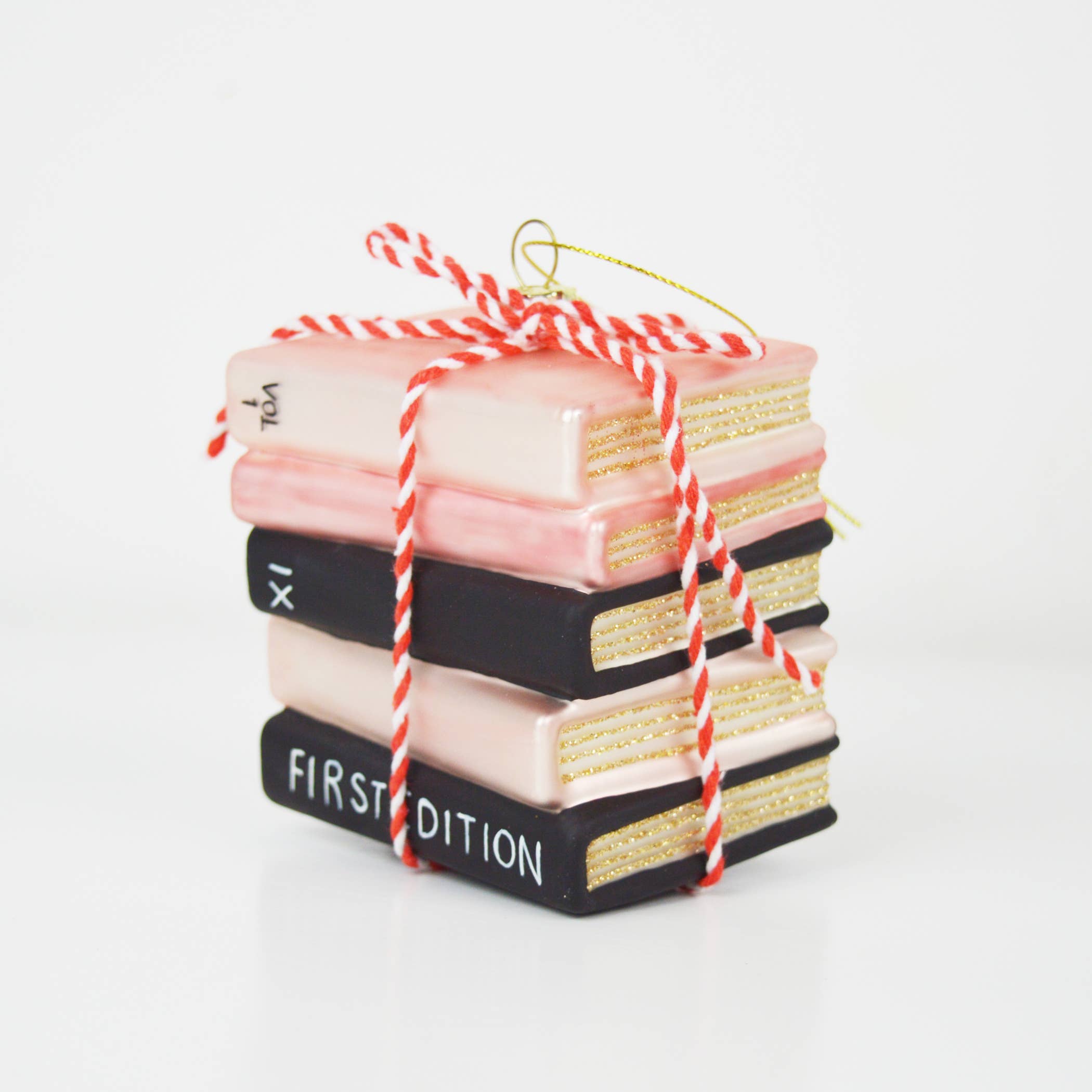Celebrate your passion for literature with this enchanting hand-painted ornament shaped like a charming stack of books. Rendered in soft pinks and classic black tones, it's finished with a delicate striped ribbon that captures the cozy warmth of a beloved bookshelf. Perfect for book lovers and reading enthusiasts, this whimsical piece brings literary charm to any holiday display or year-round décor collection.