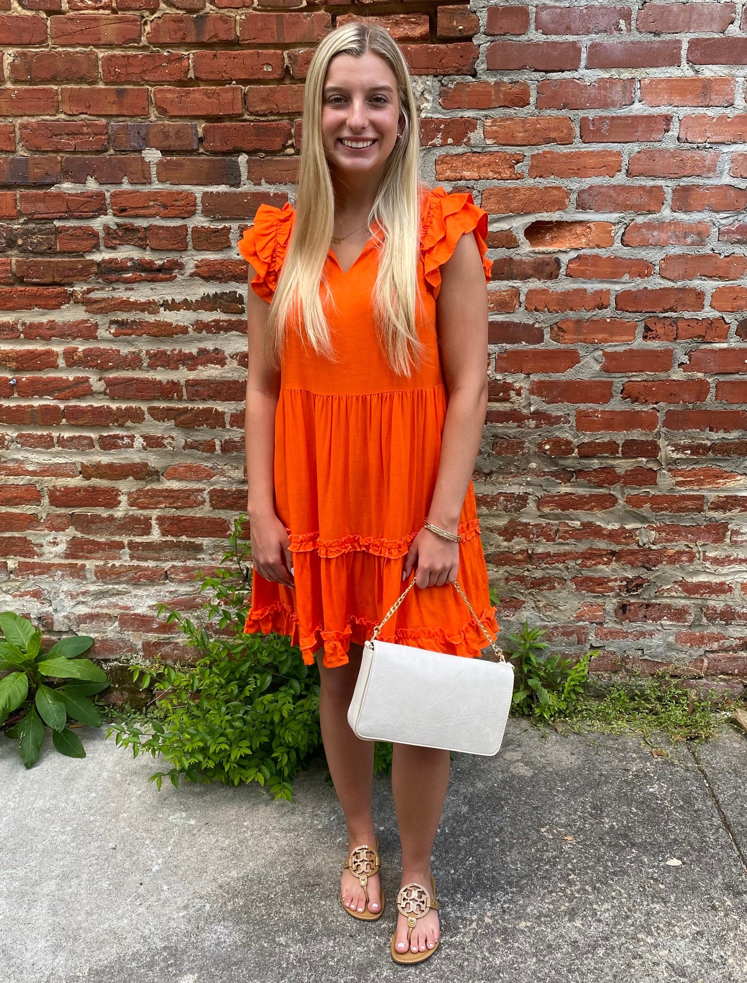 This Ruffle Sleeve V-Neck Tiered Dress is an effortless summer stunner! Its captivating ruffled cap sleeves, V-neck and tiered skirt add a fun, flirty flair to its sunny orange hue. This dress is perfect for a football Saturday in early fall!  Jenna is wearing a small.  Material: 70% Rayon / 30% Linen  Care Instructions: Hand wash cold, flat dry