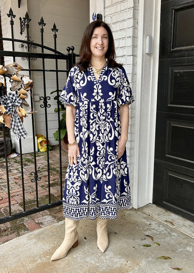 Tara in a THML navy midi dress with white print. It has fabulous detailing at the bottom and neck and a slight puffed elbow length sleeve.  