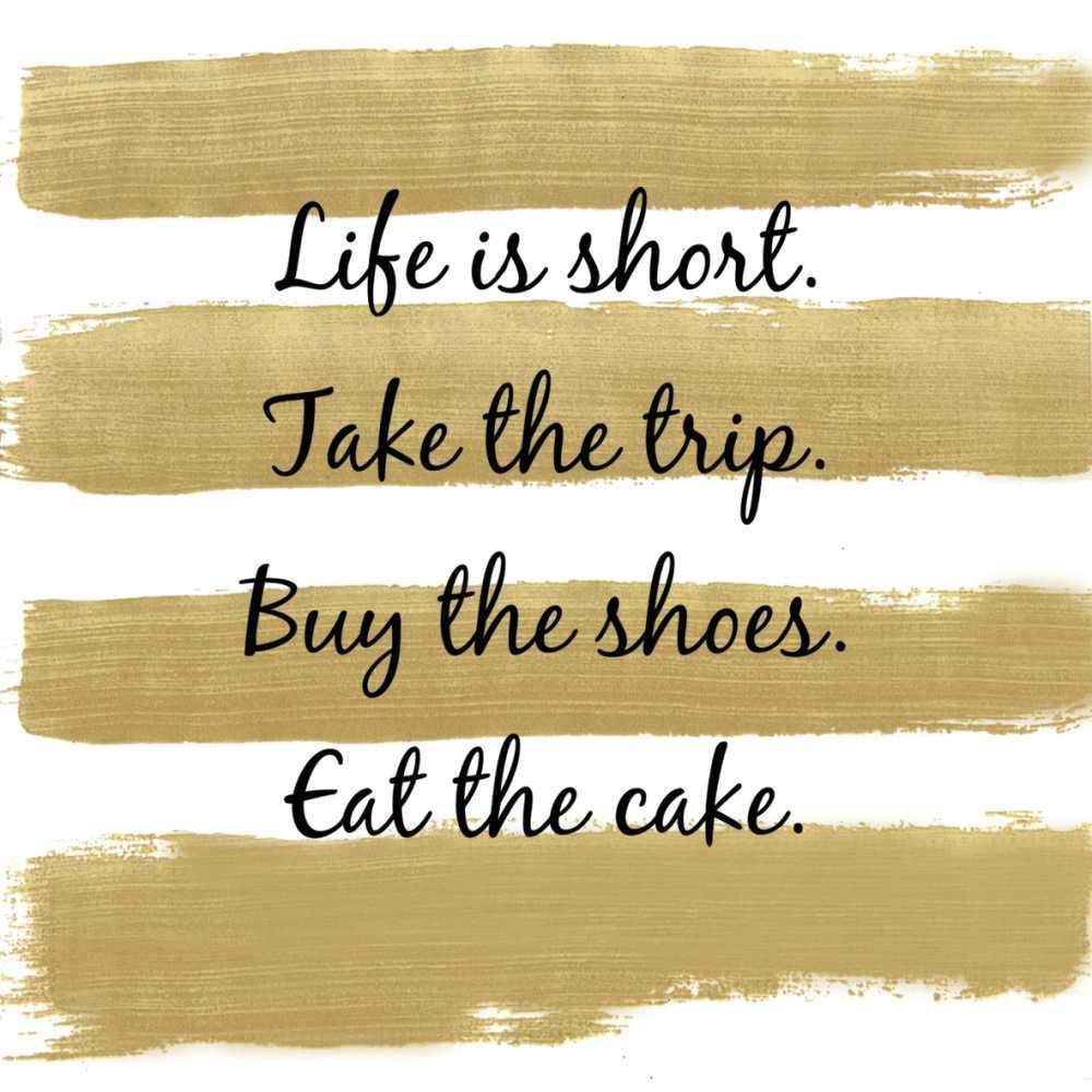 White napkin with gold stripes. Black script: Life is short. Take the trip. Buy the shoes. Eat the cake.