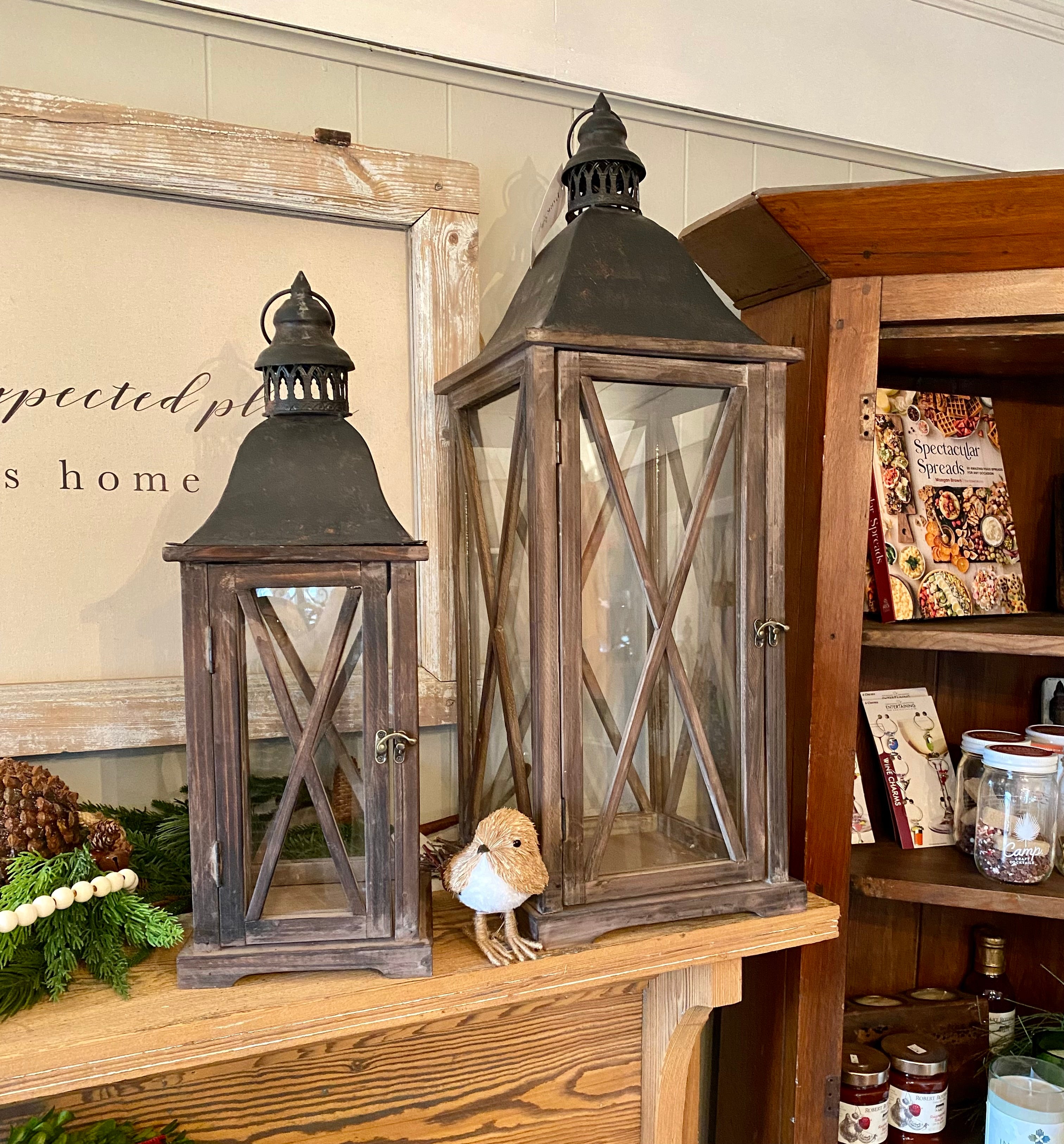These are beautiful lanterns with aged coal finished metal tops and a wood stained and waxed frame. You will love how they enhance your décor!  Details:  Materials: Fir wood, iron and glass Small: 8" x 8" x 22" Large: 10.5" x 10.5" x 31" Each lantern sold separately Shipping: Please contact us for availability and shipping of the large lantern (because of the fragile nature of shipping this product). This product is not eligible for free shipping.