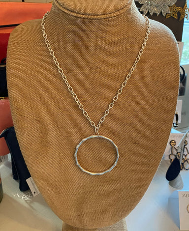 This stylish Long Bamboo-Shaped Circle Pendant Necklace features a long silver necklace, measuring 34-37" in length, and a 2.25" round bamboo shaped pendant. Its simple design and length makes it perfect for adding a subtle statement to any look.