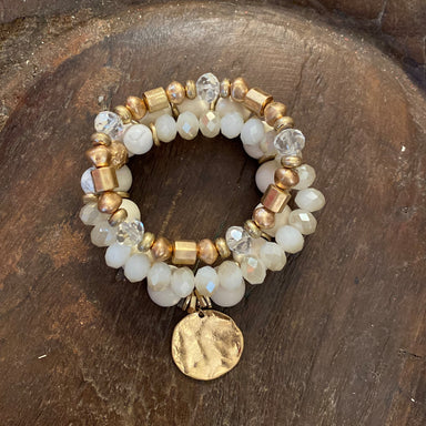 This Beaded Stretch Bracelet Set is a stylish accessory, crafted with ivory, clear crystal, and gold beads, and finished with a unique hammered disc charm. An elegant addition to any look, it offers a timeless combination of classic and modern style. Set of 3.