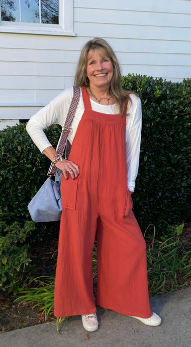 What a fun and versatile jumpsuit in a beautiful rust! You can wear it throughout the year as it can be paired with bralette/camisole, t-shirt or sweater - any number of tops will work. The wide legs are a beautiful touch!  Material: 100% Cotton  Care Instructions: Hand wash cold, hang/flat dry