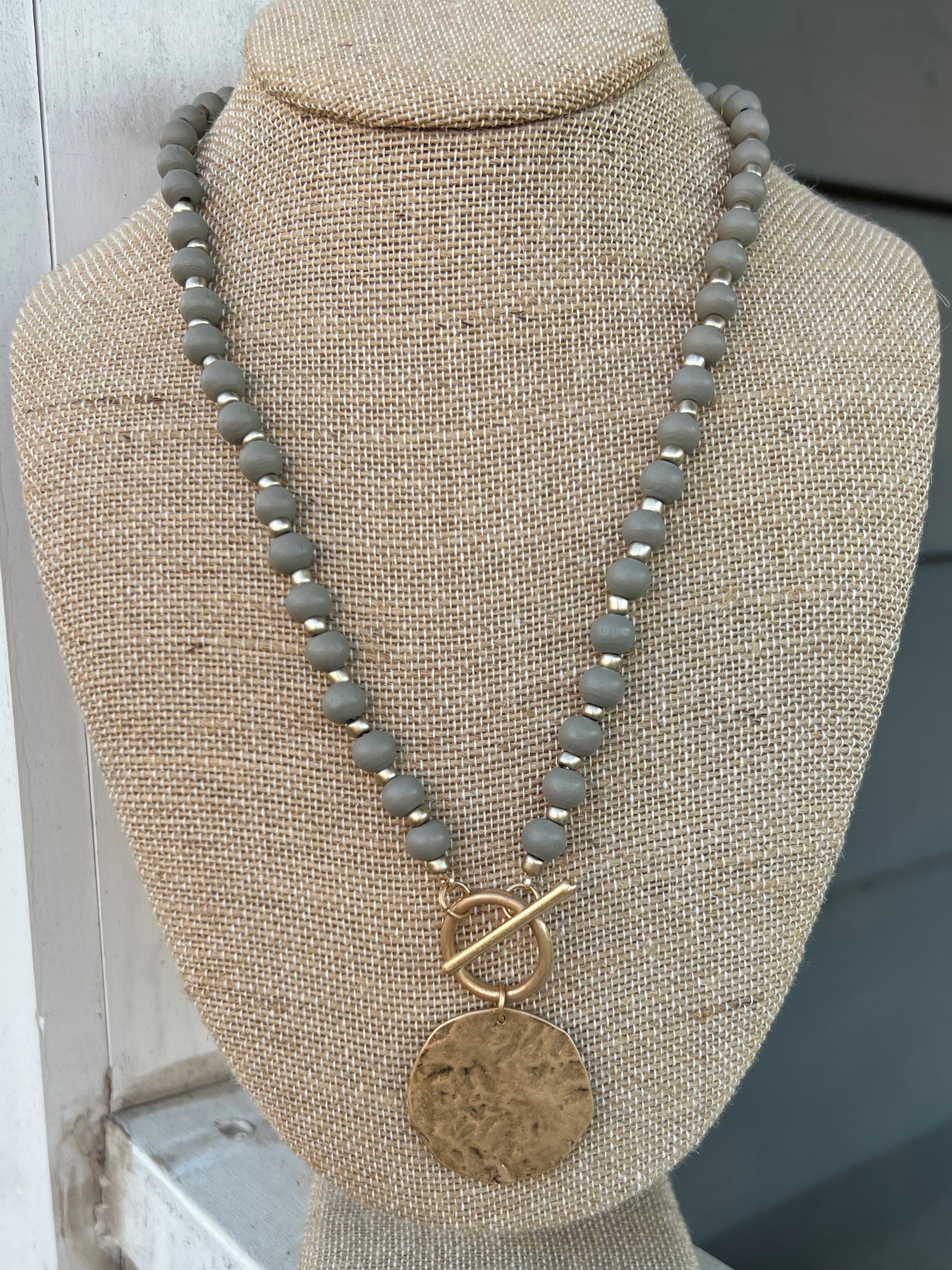 We love these wood beaded necklaces that add a little bit of dimension! They are topped off by the beautiful hammered gold coin charm. The necklace is approximately 20-23" in length and the gold charm is approximately 1.25" in diameter. This necklace will look great with your favorite cozy sweater or a lovely sleek dress - this necklace is so versatile!