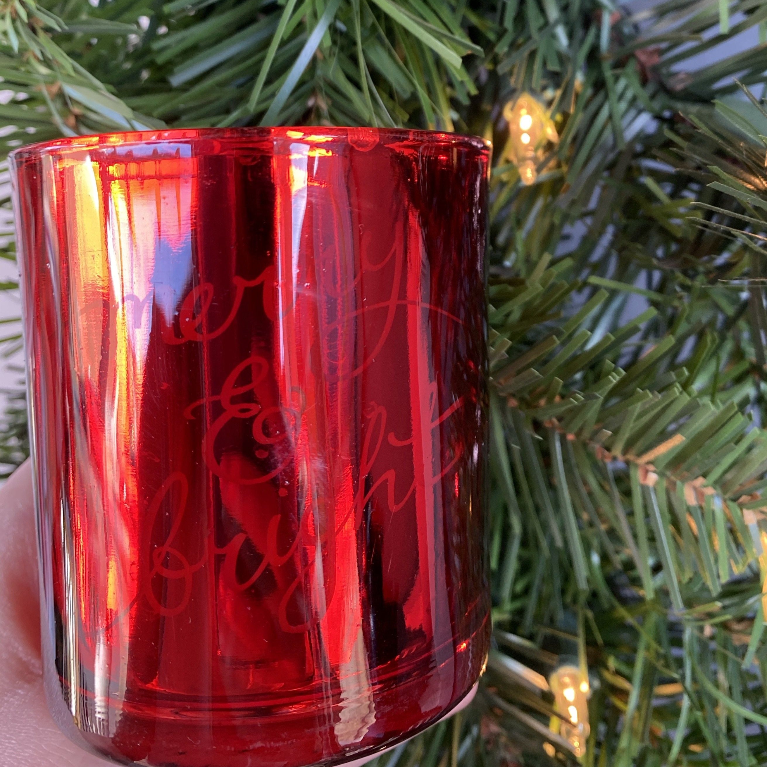 Shiny red glass candle says Merry & Bright in script