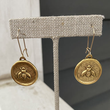 Gold drop medallion earrings featuring a bee design