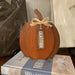 Rustic finished, orange wooden 2 dimensional pumpkin with brown stem, raffia bow and tag says Gratitude