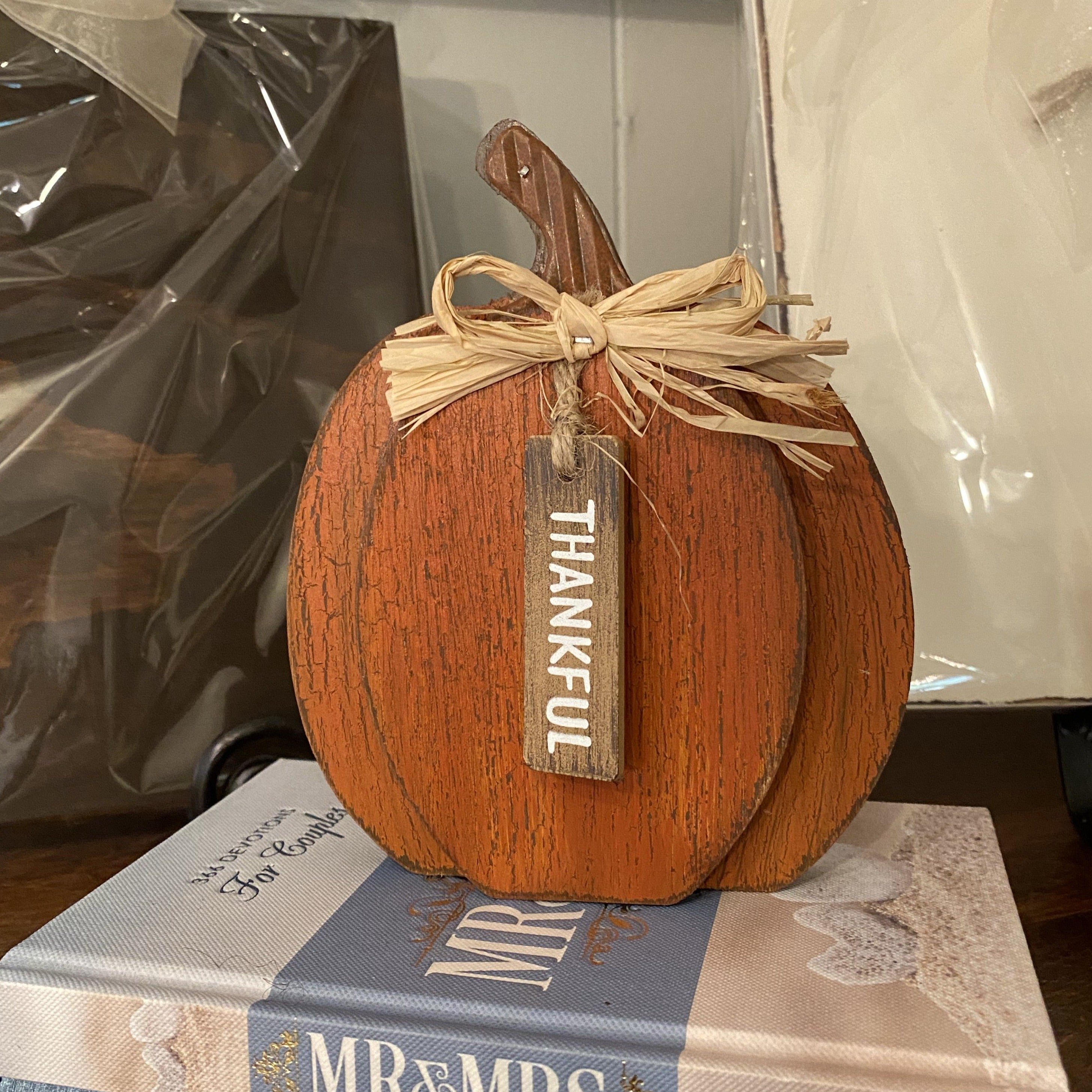 Rustic finished, orange wooden 2 dimensional pumpkin with brown stem, raffia bow and tag says Thankful