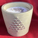 Candle in a concrete-like container with raised Christmas tree design made of five point stars