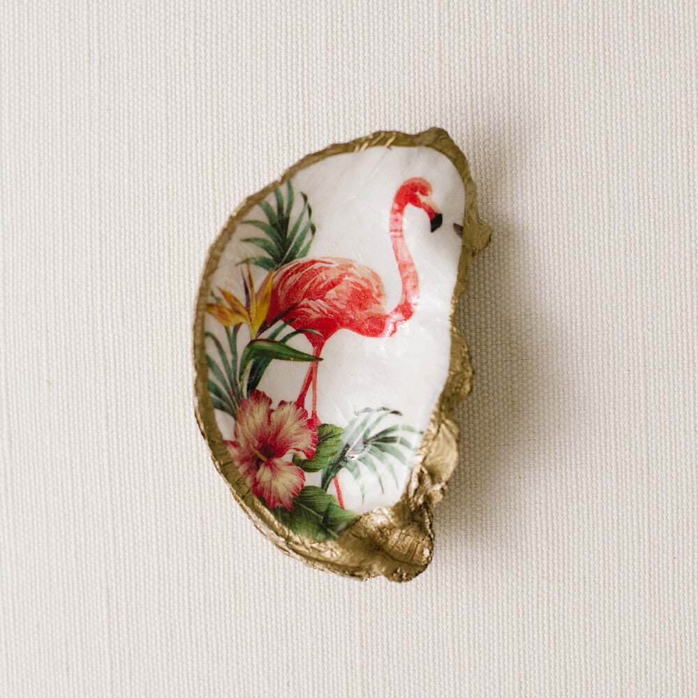 Grits and grace oyster shell painted with pink flamingo among tropical flowers and plants